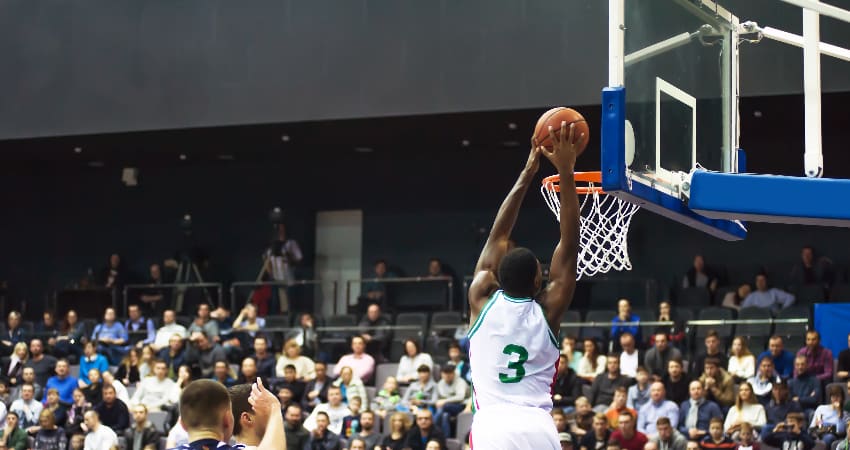 A basketball player lands a lay-up in a packed stadium